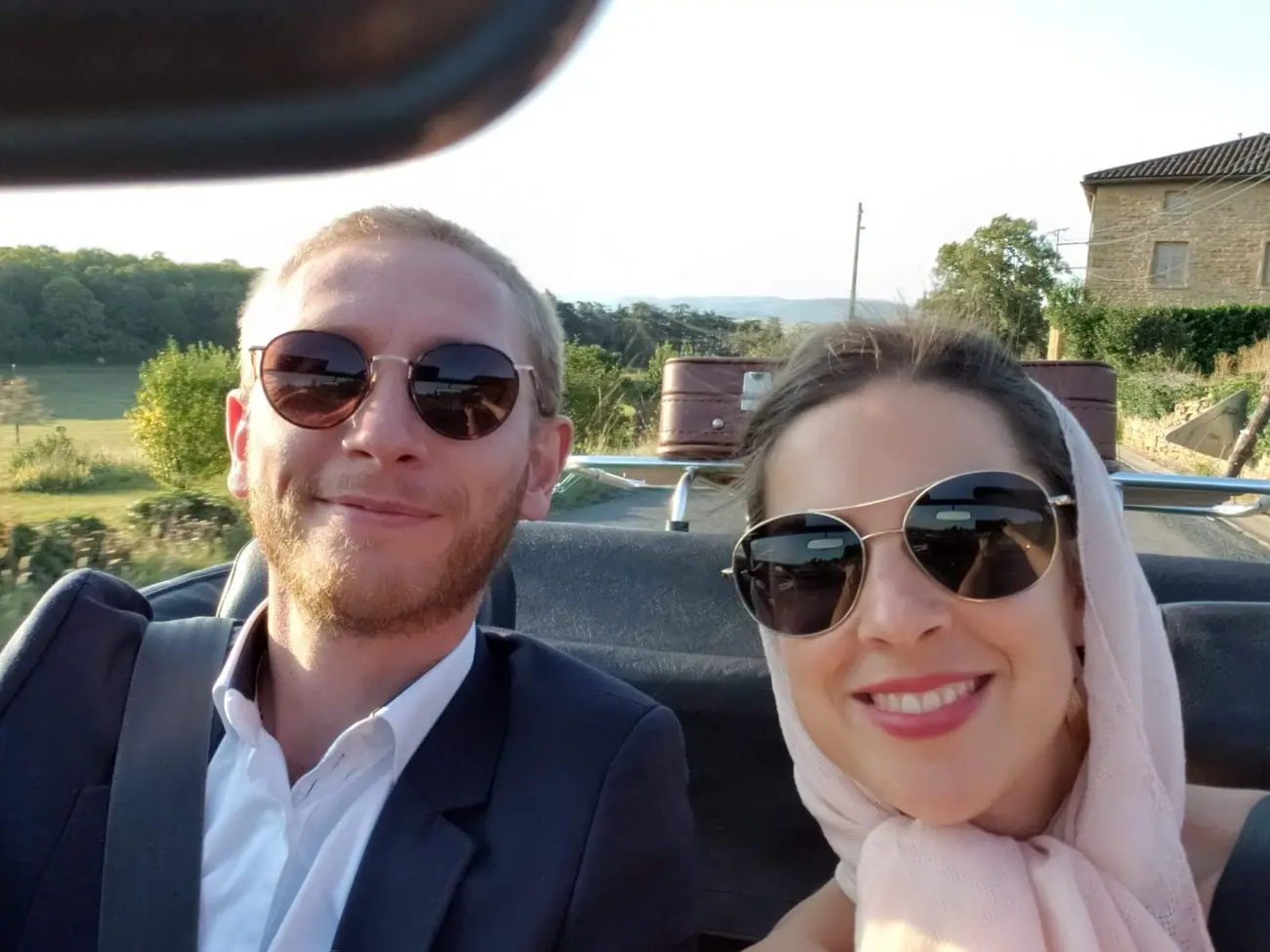 Maud et Simon en lunettes de soleil dans une voiture décapotable, Maud avec un foulard rose