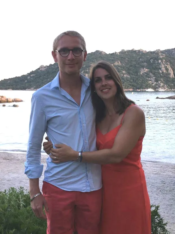 Maud et Simon enlacés au bord de la mer, elle en robe corail, lui en chemise bleue